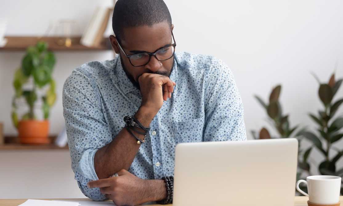 man looking at laptop deciding between stocks or ETFs