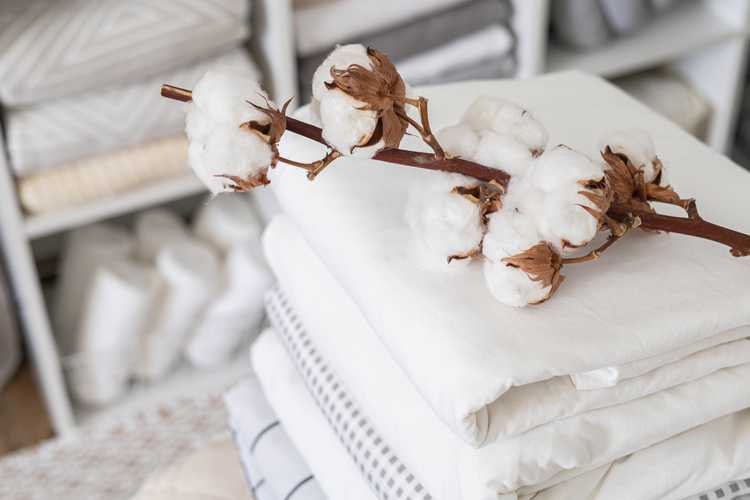 Cotton branch with pile of folded bed sheets and blankets